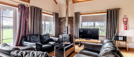 Ein Wohnzimmer mit Kamin, Ledersofas, Fernseher und Holzboden.