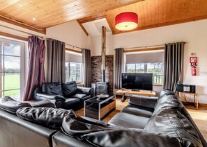 Ein Wohnzimmer mit Kamin, Ledersofas, Fernseher und Holzboden.