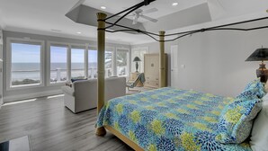 Un dormitorio con una cama grande, un ventilador de techo y vistas al océano.