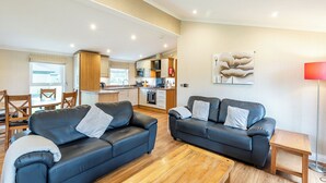 A living room with two sofas, a wooden coffee table, and a kitchen in the background. - Lakeside 2 Pet Friendly (Woodhall Spa)