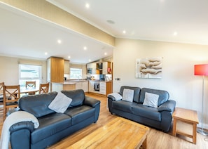 Ein Wohnzimmer mit zwei Sofas, einem Holztisch und einer Küche im Hintergrund.