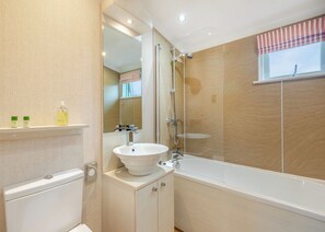 Ein modernes Badezimmer mit Waschbecken in Weiß, einer Duschkabine und einem Fenster mit gestreiften Vorhängen.