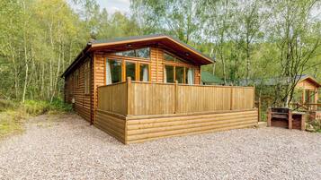 Une cabane en bois dotée d’une terrasse, entourée d’arbres.
