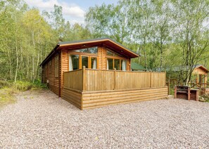 A wooden cabin with a deck, surrounded by trees. - 3 bedroom accommodation in Freehay, Cheadle (Freehay, Cheadle)