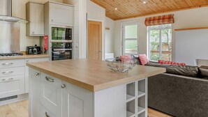 A modern kitchen with white cabinets, a wooden countertop, and a built-in oven. - 3 bedroom accommodation in Freehay, Cheadle (Freehay, Cheadle)