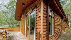 Eine Blockhütte mit großen Glasüren, einer Holzdiele und einem Picknicktisch.