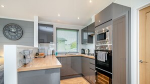 Una cocina moderna con horno empotrado, microondas y pileta.