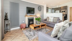 Una sala de estar moderna con chimenea, sofá, mesa de centro y televisor.
