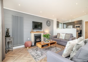 A modern living room with a fireplace, sofa, coffee table, and a television.