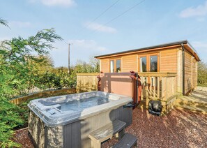 Una cabaña de madera con jacuzzi y terraza.
