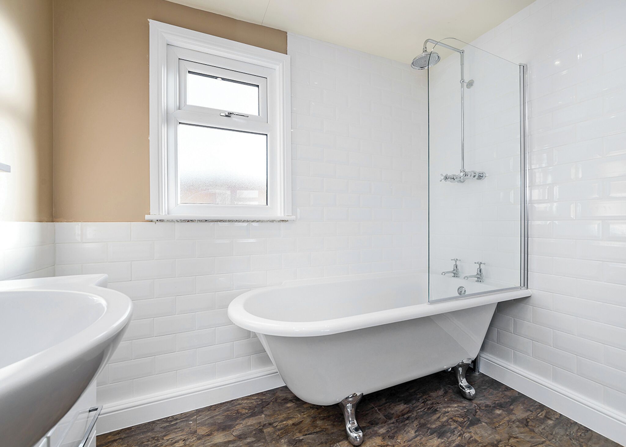 Ein Badezimmer mit freistehender Badewanne, einer Duschkabine und einem Fenster.