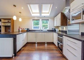 A modern kitchen with skylights, a central island, and a view of greenery outside.