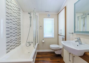 A bathroom with a shower, toilet, sink, and window.