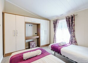 A bedroom with two beds, a wardrobe, a vanity, and a window with curtains. - 2 bedroom accommodation in Calthwaite, Nr Penrith (Calthwaite, Nr Penrith)