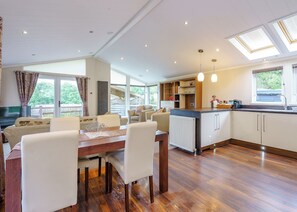 A spacious living area with a dining table, chairs, a sofa, a kitchen with a countertop, and a view of the outdoors.