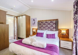 A hotel room with a large bed, two bedside tables, a wardrobe, and a shower area.