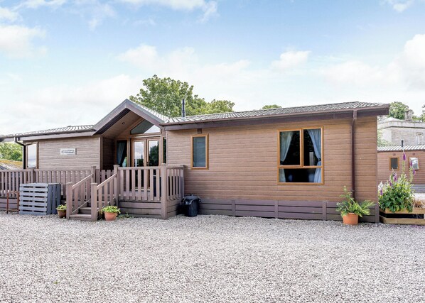A wooden cabin with a porch, a staircase, and a gravel driveway.