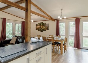 Una cocina moderna con encimera de mármol, vigas de madera y un comedor con mesa dispuesta para cuatro.