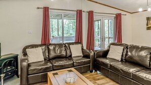 Une pièce comprenant deux canapés en cuir, une table basse en bois et une fenêtre avec des rideaux.
