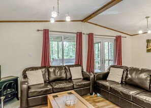 A room with two leather sofas, a wooden coffee table, and a window with curtains.
