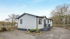 A single-story mobile home with a front porch, a gravel driveway, and a wooden fence. - 1 bedroom accommodation in Dumfries, Dumfries & Galloway (Dumfries, Dumfries & Galloway)