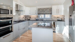 A modern kitchen with stainless steel appliances, white cabinetry, a central island, and a large window. - 1 bedroom accommodation in Dumfries, Dumfries & Galloway (Dumfries, Dumfries & Galloway)