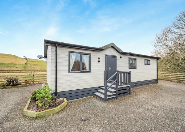A single-story mobile home with a front porch, a door, and two windows.