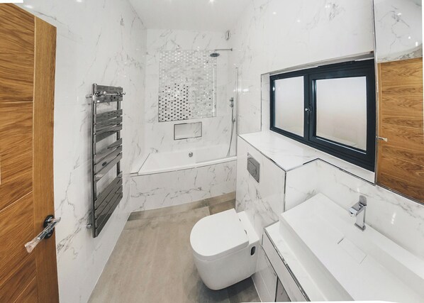 A modern bathroom with a toilet, sink, shower, and a wooden door. - Two bed lodge with one king-size bed and one twin (King by arrangement). (Nottingham)