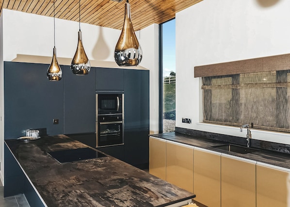 A modern kitchen with a central island, built-in oven, and pendant lighting. - Two bed lodge with one king-size bed and one twin (King by arrangement). (Nottingham)