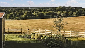 A rural landscape with a fenced field, a wind turbine, and a distant hill. - Two bed lodge with one king-size bed and one twin (King by arrangement). (Nottingham)
