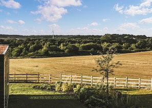 A rural landscape with a fenced field, a wind turbine, and a distant hill. - Two bed lodge with one king-size bed and one twin (King by arrangement). (Nottingham)