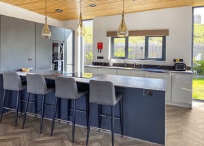 A modern kitchen with a central island, bar stools, and pendant lighting. - Two bed lodge with one king-size bed and one twin (King by arrangement). (Nottingham)