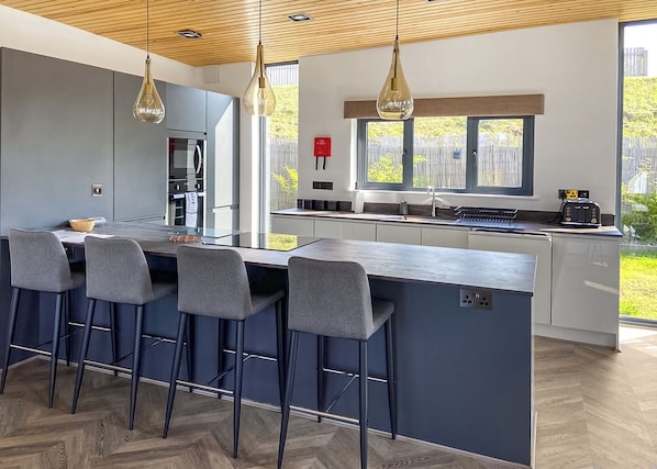 A modern kitchen with a central island, bar stools, and pendant lighting. - Two bed lodge with one king-size bed and one twin (King by arrangement). (Nottingham)