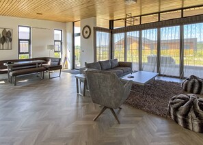 A spacious living area with a herringbone floor, a sofa, a coffee table, and a bench.