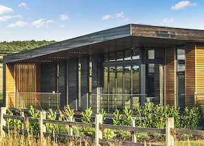 A modern building with large windows, a wooden fence, and a grassy area. - Two bed lodge with one king-size bed and one twin (King by arrangement). (Nottingham)