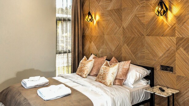 Une chambre d’hôtel avec un lit, des oreillers, une table de chevet et un luminaire fixé au mur.