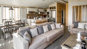 A modern living room with a sofa, coffee table, and dining area. - Lakeside 14 Casa Pet Friendly (Woodhall Spa)