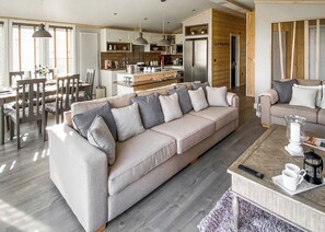 A modern living room with a sofa, coffee table, and dining area. - Lakeside 14 Casa Pet Friendly (Woodhall Spa)
