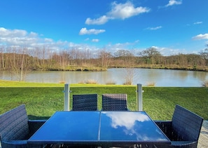 Een tafel en stoelen met uitzicht op een meer en bomen.