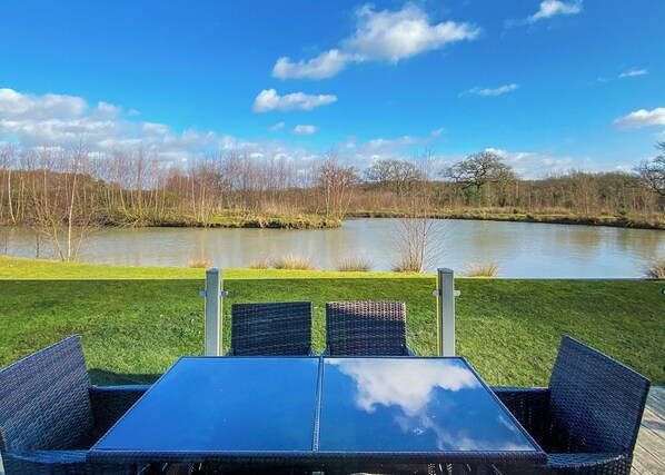 A table and chairs with a view of a lake and trees.