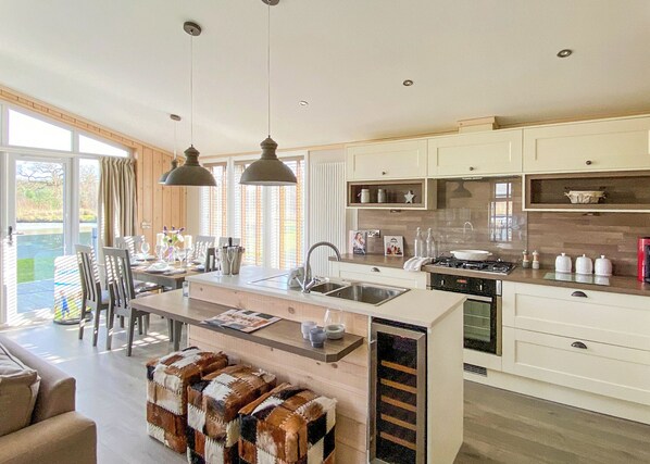 A modern kitchen with a central island, pendant lighting, and a view to the outside.