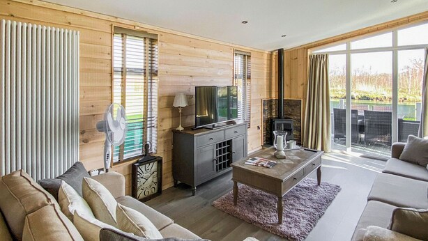 A modern living room with a sofa, coffee table, TV, and fireplace. - Lakeside 14 Casa Pet Friendly (Woodhall Spa)
