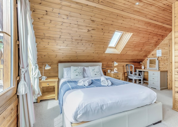A cozy bedroom with a bed, bedside tables, a desk, and a chair. - 3 bedroom accommodation in Anglesey (Anglesey)