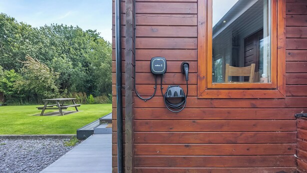 A wooden cabin with a window, a picnic table, and outdoor electrical outlets.