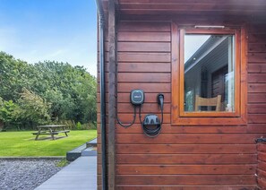 A wooden cabin with a window, a picnic table, and outdoor electrical outlets.
