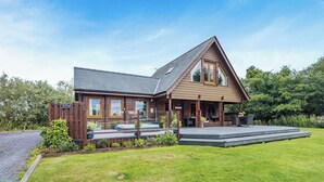 A wooden house with a sloped roof, a porch, and a front yard.