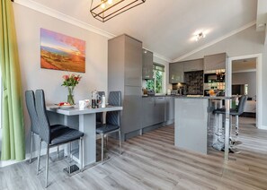 A modern kitchen with a dining area, featuring a large island, stainless steel appliances, and a view of the outdoors.
