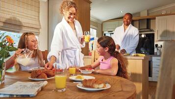Un petit-déjeuner en famille dans une cuisine moderne, avec des meubles en bois, une table à manger et une vue sur l’extérieur.