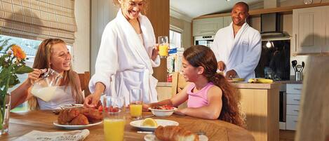 Un desayuno familiar en una cocina moderna con armarios de madera, una mesa de comedor y vistas al exterior.