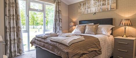 Ein Schlafzimmer mit einem Bett, Nachttischen, Vorhängen an einem Fenster und einem Bild an der Wand.
